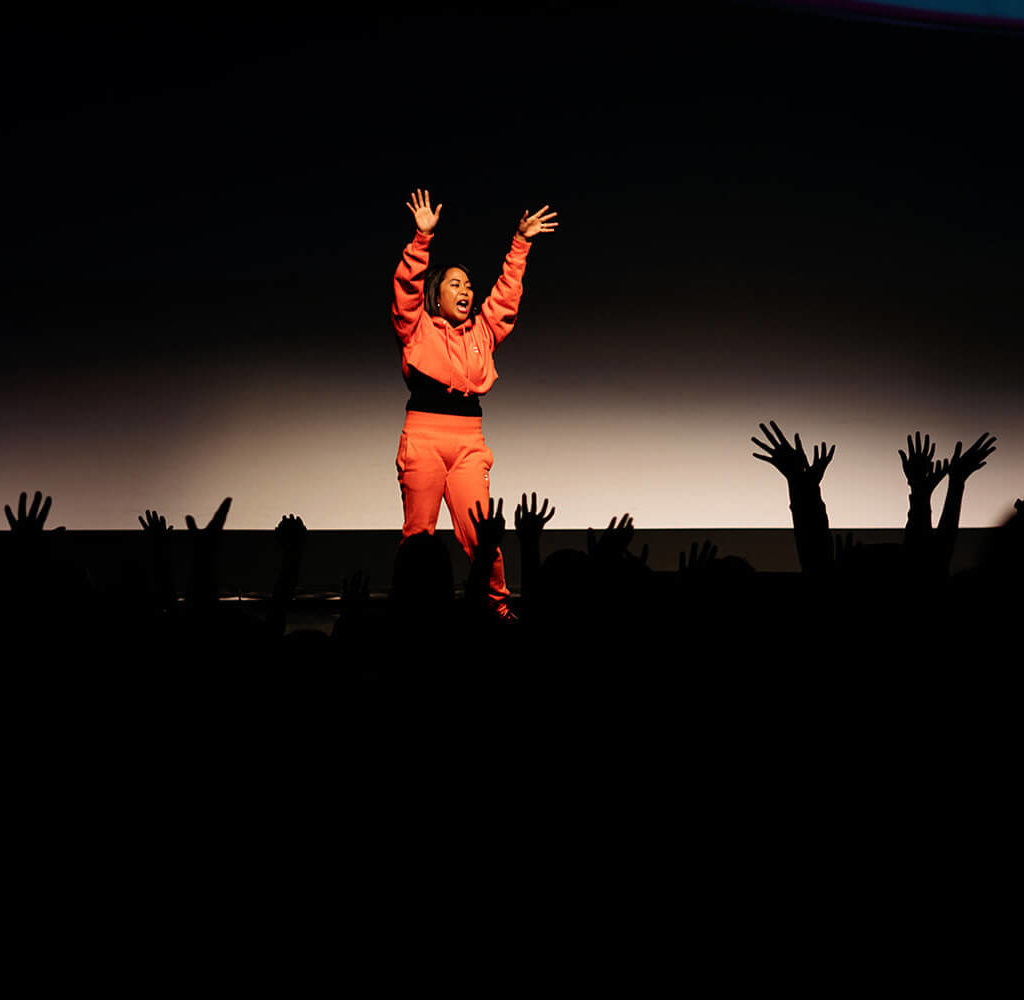 Janet wearing orange speaking on stage